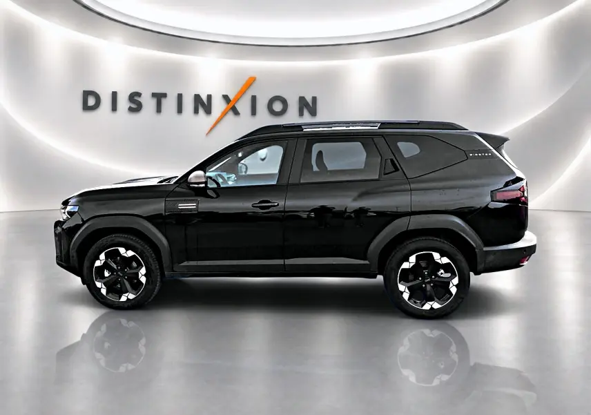 Profil droit du Dacia Bigster noir 2025 avec jantes alu distinctives et barres de toit visibles en intérieur showroom.