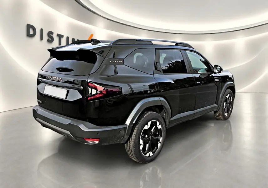 Vue 3/4 arrière droite d'un Dacia Bigster noir avec barres de toit et jantes alu distinctives.