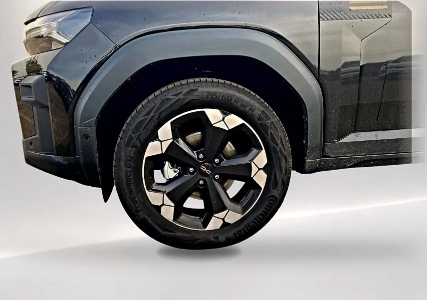 Gros plan sur la roue avant gauche noire du Dacia Bigster 2025 avec jante alu bicolore et passage de roue noir.