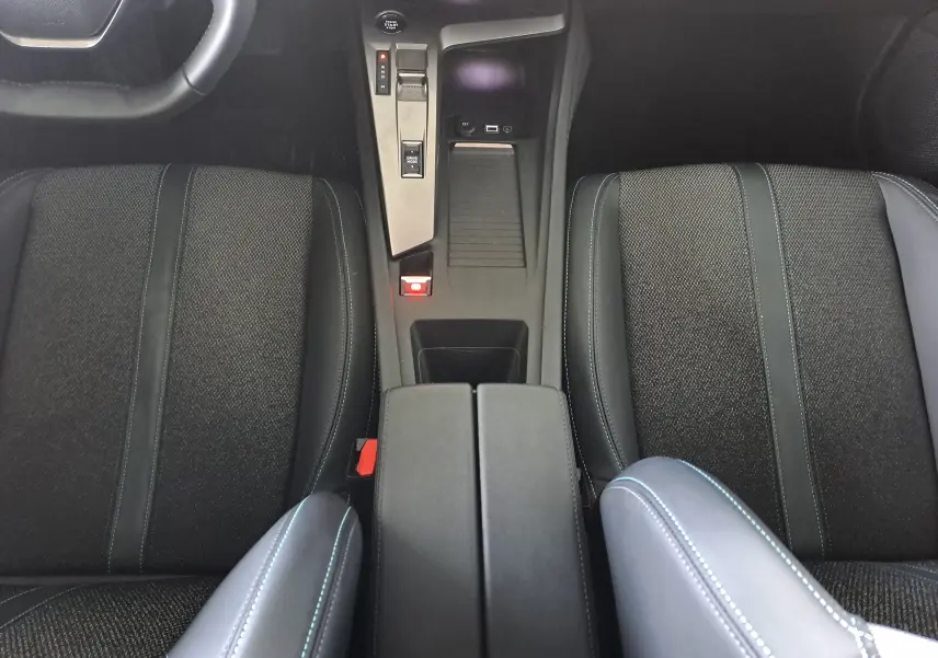 Vue intérieure centrée sur la console centrale et les sièges noirs du Peugeot 308 1.5 BlueHDi 130ch Allure 2024.