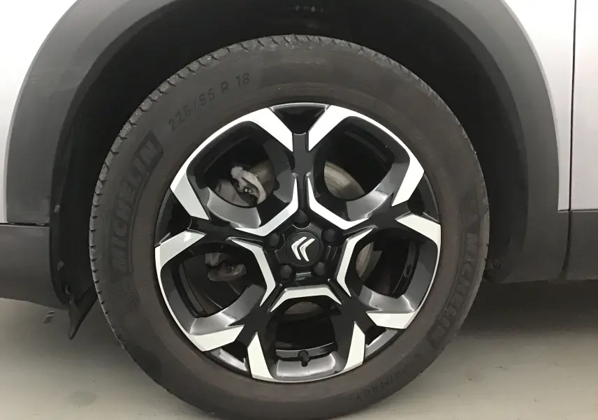 Gros plan sur la roue avant gauche du Citroën C5 Aircross 2024 gris Artense avec jante alliage noire et argentée.