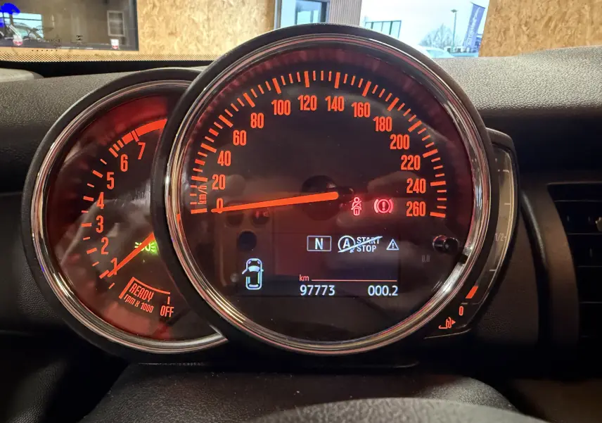 Vue rapprochée du tableau de bord de la MINI noire 2018, affichant le compteur de vitesse et le compte-tours éclairés en orange.