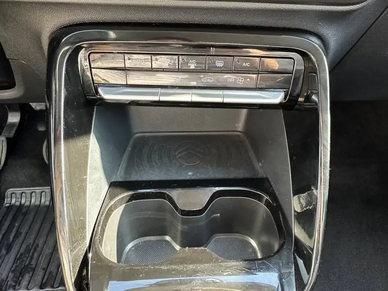 Vue rapprochée de la console centrale noire du Citroën C3 2025, avec commandes climatisation et porte-gobelets.