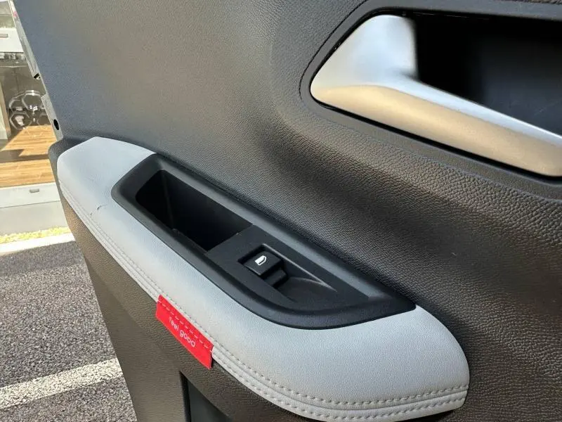 Détail de la porte intérieure côté gauche de la Citroën C3 gris Mercury, avec commande de vitre et surpiqûres grises.