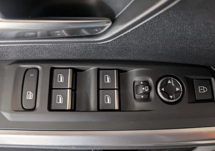 Vue rapprochée des commandes de lève-vitres et rétroviseurs sur la porte côté gauche d’un Peugeot 5008 Hybrid blanc.
