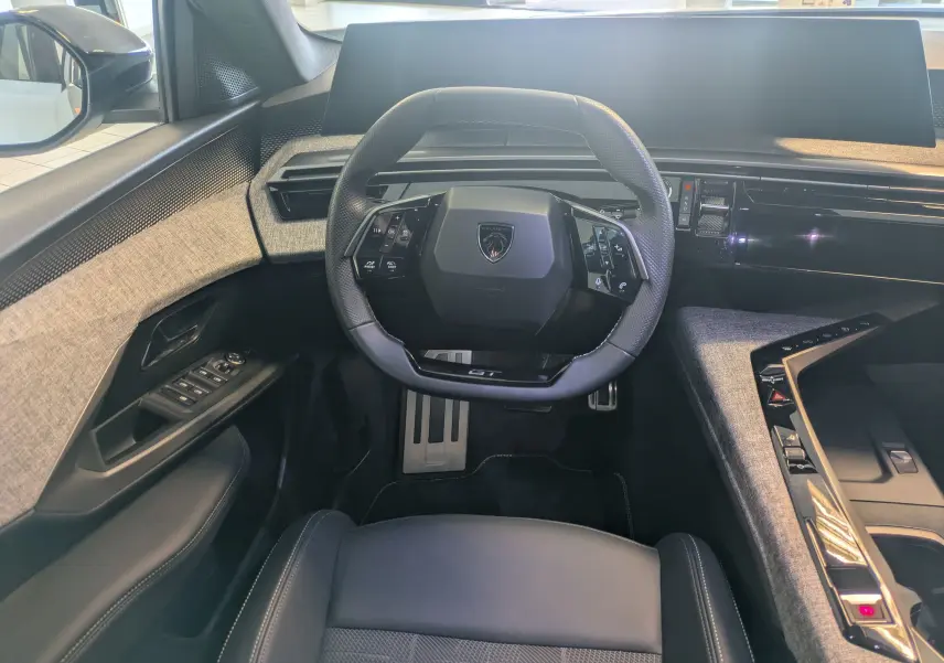 Vue intérieure frontale du Peugeot 5008 Hybrid 145 GT avec volant compact, tableau de bord numérique et habillage tissu gris.