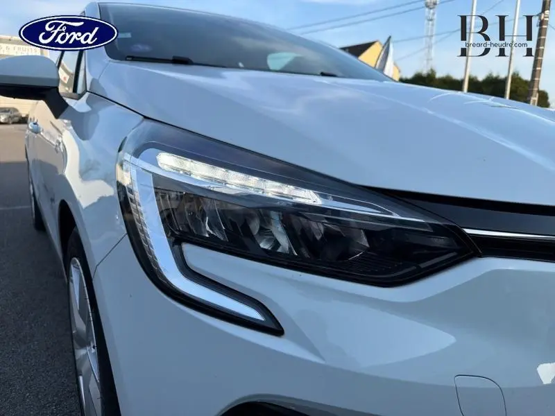 Gros plan sur le phare avant gauche blanc d'une Renault Clio 1.6 E-Tech 140ch Business de 2021.
