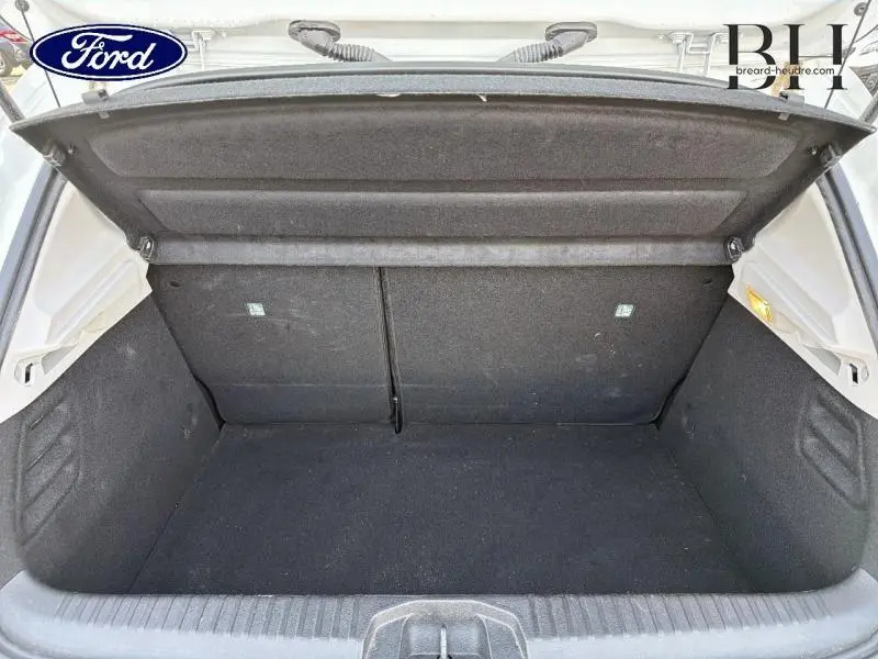 Coffre ouvert d'une Renault Clio blanche, vue de l'arrière montrant un espace de chargement noir et propre.