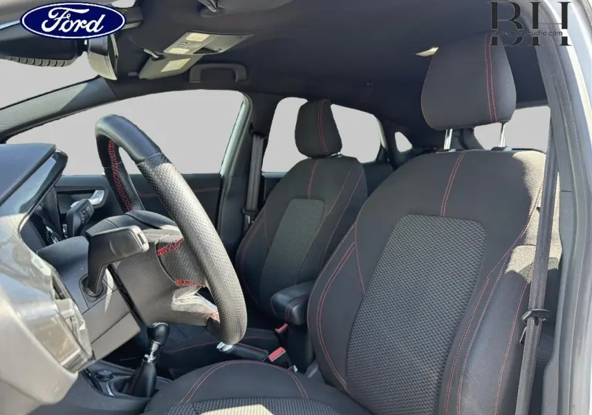 Vue intérieure côté conducteur du Ford Puma 2023, sièges noirs avec surpiqûres rouges et volant sport multifonction.