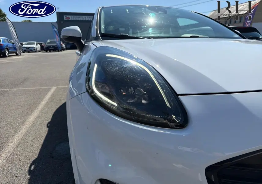Gros plan sur le phare avant gauche du Ford Puma blanc glacier, mettant en valeur son éclairage LED distinctif.