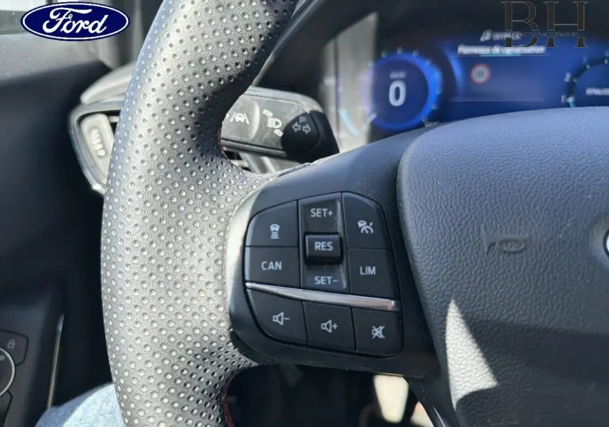 Vue rapprochée du volant sport perforé avec commandes multifonctions du Ford Puma 2023, ambiance intérieure noire.