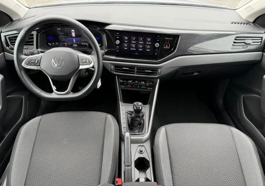 Vue intérieure frontale du tableau de bord et volant cuir multifonctions du Volkswagen Taigo gris reflet d'argent, avec boîte manuelle.