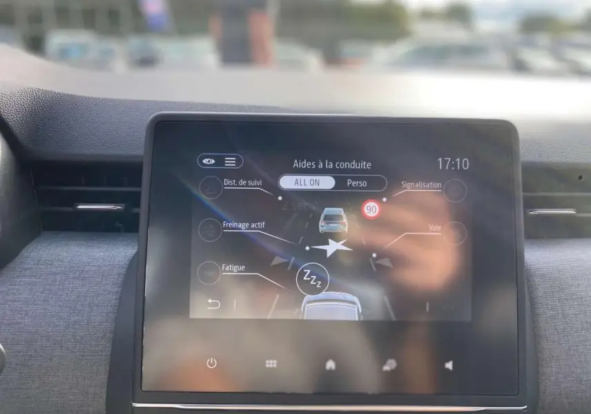 Écran tactile central de la Renault Clio 2025 montrant les aides à la conduite dans un intérieur sombre.
