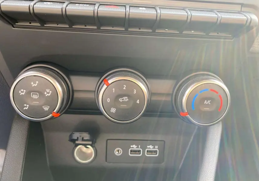 Gros plan sur les commandes de climatisation manuelle et ports USB de la Renault Clio Evolution 2025 en intérieur.