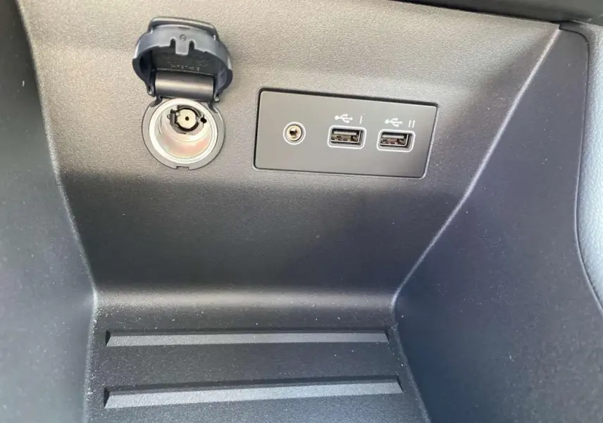 Prise allume-cigare et double port USB visibles dans le rangement intérieur de la Renault Clio Evolution noire étoile 2025.