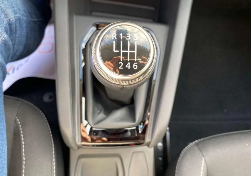 Gros plan sur le levier de vitesse manuel noir de la Renault Clio 2025, finition Evolution, avec surpiqûres blanches visibles.