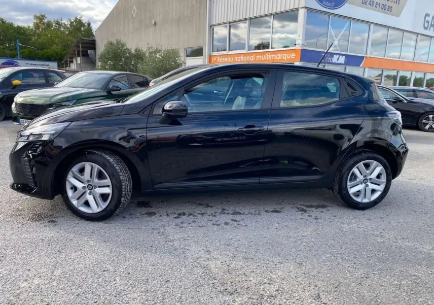 Profil côté gauche d'une Renault Clio 2025 noire étoile, garée devant un bâtiment commercial avec d'autres voitures visibles.