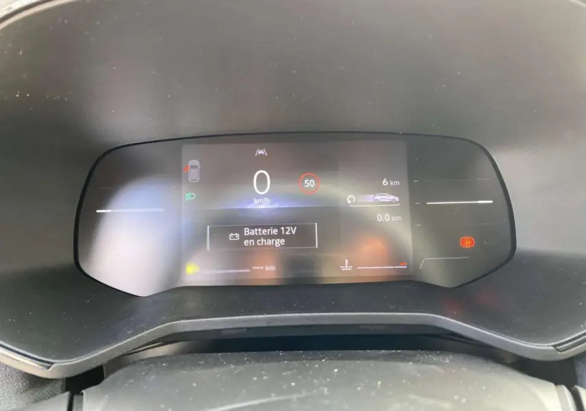 Tableau de bord numérique de Renault Clio 2025 affichant vitesse, alertes et batterie en charge, vue frontale intérieure.