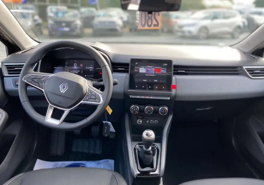 Vue intérieure avant de la Renault Clio Evolution 2025 avec volant multifonction, écran tactile et levier de vitesse manuel.