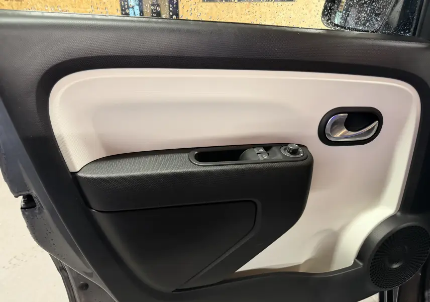 Intérieur de la porte côté gauche de la Renault Twingo III 2018, avec panneaux noir et beige et commandes électriques.