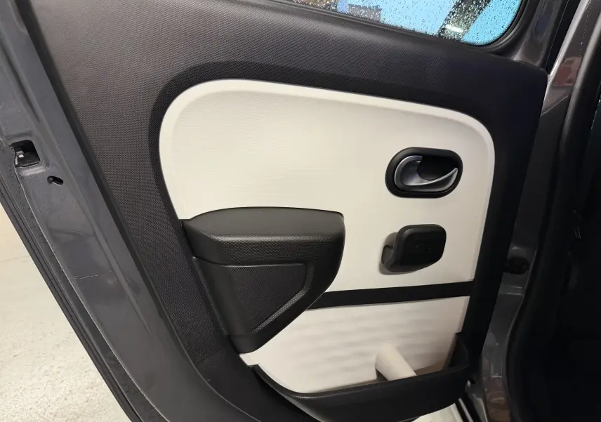 Vue rapprochée de la portière arrière droite gris métallisé de la Renault Twingo III avec panneau intérieur bicolore noir et blanc.