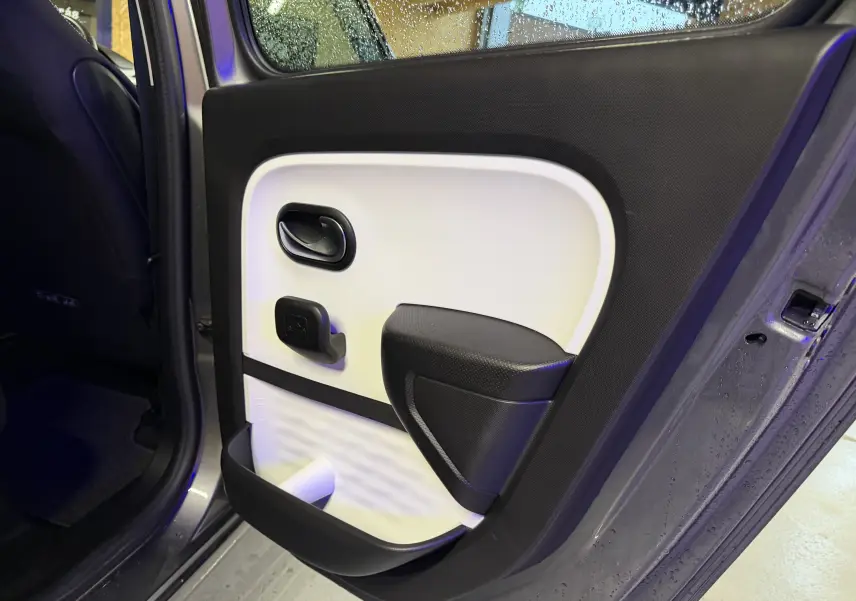 Vue intérieure côté gauche de la porte arrière grise de la Renault Twingo III 2018 avec habillage bicolore noir et blanc.
