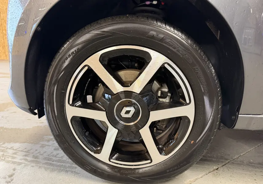 Gros plan sur la roue avant droite d'une Renault Twingo III gris avec jante alliage bicolore et logo Renault central.