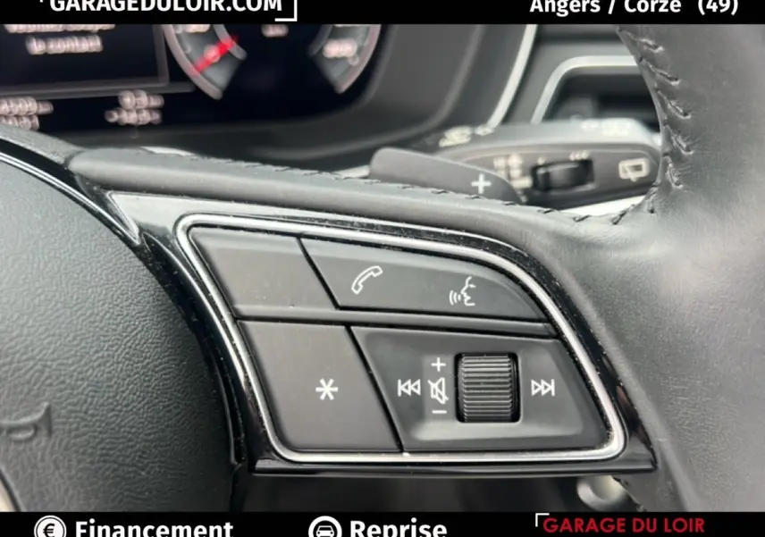 Gros plan sur les commandes au volant cuir noir de l'Audi A4 40 TFSI ultra 190 S tronic Avus, avec boutons multifonctions.