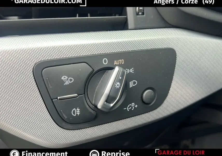 Gros plan sur la commande des phares à gauche du tableau de bord d'une Audi A4 noire, avec réglage automatique et antibrouillard.