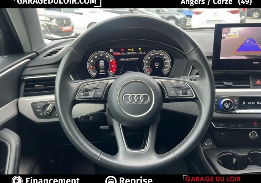 Vue intérieure centrée sur le volant cuir noir et le tableau de bord numérique d'une Audi A4 noire de 2020.