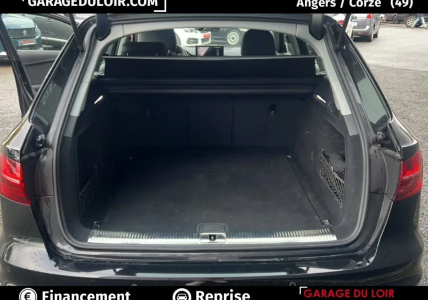Coffre ouvert d’une Audi A4 noire vue de l’arrière, montrant l’espace de chargement et la plage arrière.