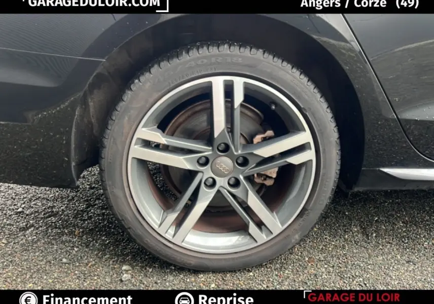 Gros plan sur la roue arrière droite d'une Audi A4 noire, mettant en valeur la jante alliage cinq branches.