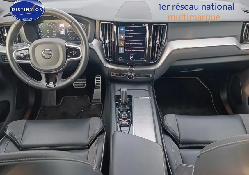 Vue intérieure avant du Volvo XC60 blanc 2021, tableau de bord moderne avec écran tactile central et volant cuir multifonction.