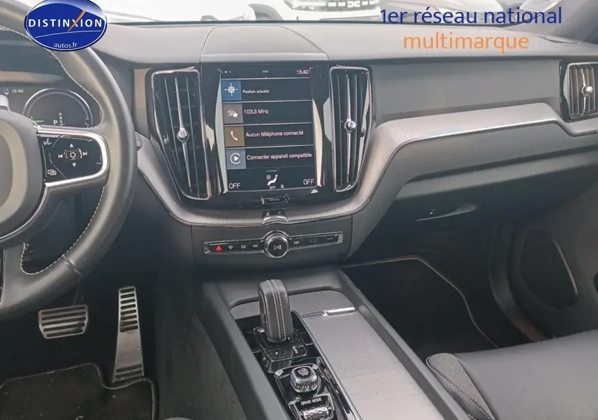 Vue intérieure du tableau de bord et console centrale du Volvo XC60 blanc, avec écran tactile et volant multifonction.