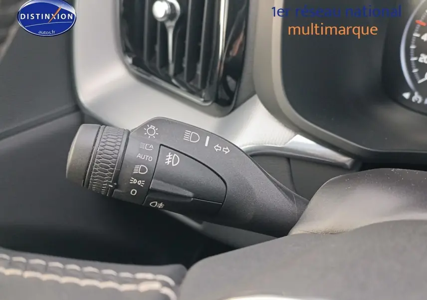 Gros plan sur la commande des feux et clignotants à gauche du volant dans l'habitacle du Volvo XC60 blanc.