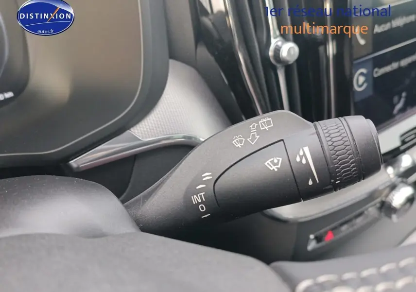 Gros plan sur la commande des essuie-glaces dans l’habitacle d’un Volvo XC60 blanc, avec tableau de bord partiellement visible.