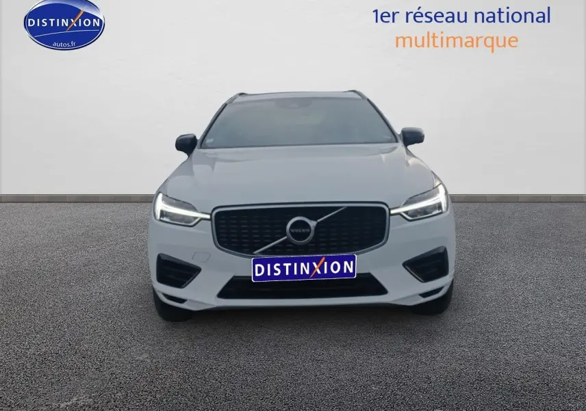Vue frontale d'un Volvo XC60 blanc avec calandre noire et phares LED allumés sur fond neutre.