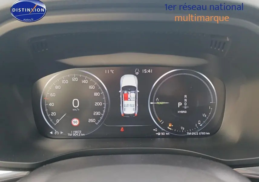 Tableau de bord numérique du Volvo XC60 blanc, affichant vitesse, mode hybride et état des portes ouvertes.