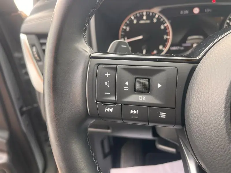 Gros plan sur les commandes multifonctions noires du volant cuir du Nissan Qashqai 2022, intérieur gris.