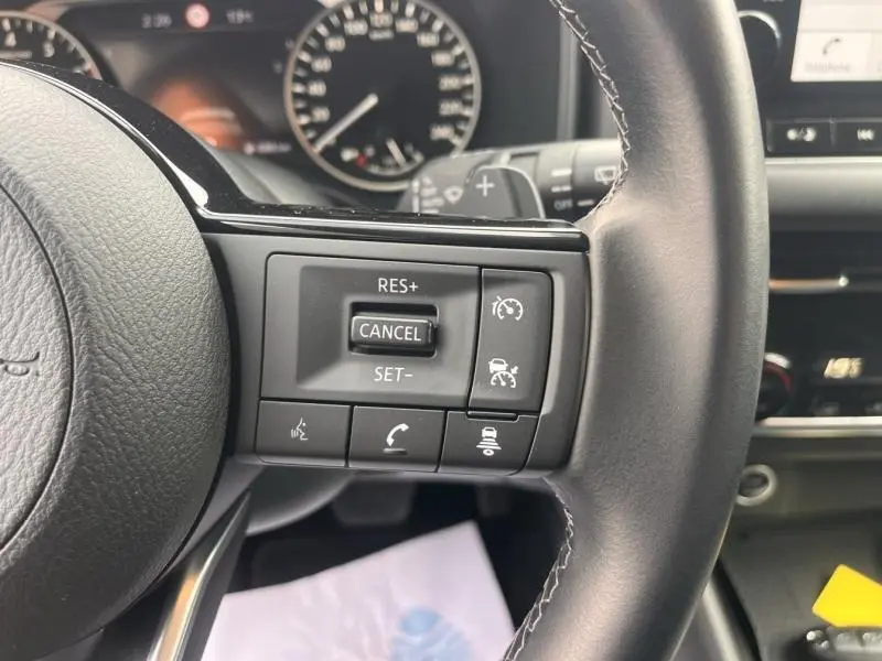 Gros plan sur les commandes multifonctions du volant cuir noir du Nissan Qashqai 2022, avec boutons de régulateur de vitesse.
