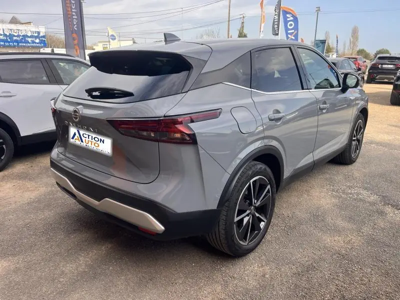 Vue 3/4 arrière droite du Nissan Qashqai gris argile avec toit noir et jantes alliage noires sur parking.