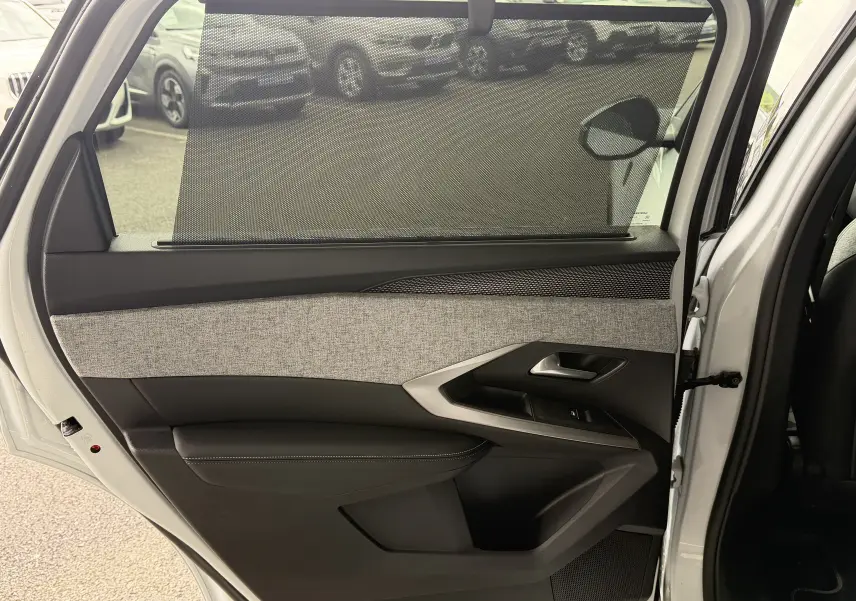 Vue intérieure de la porte arrière droite blanche du Peugeot 5008 Hybrid 145 GT avec pare-soleil et garniture tissu gris.