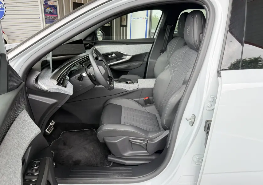 Vue intérieure côté conducteur du Peugeot 5008 Hybrid 145 e-DCS6 GT blanc, sièges tissu/tep gris avec surpiqûres Iced Clay.