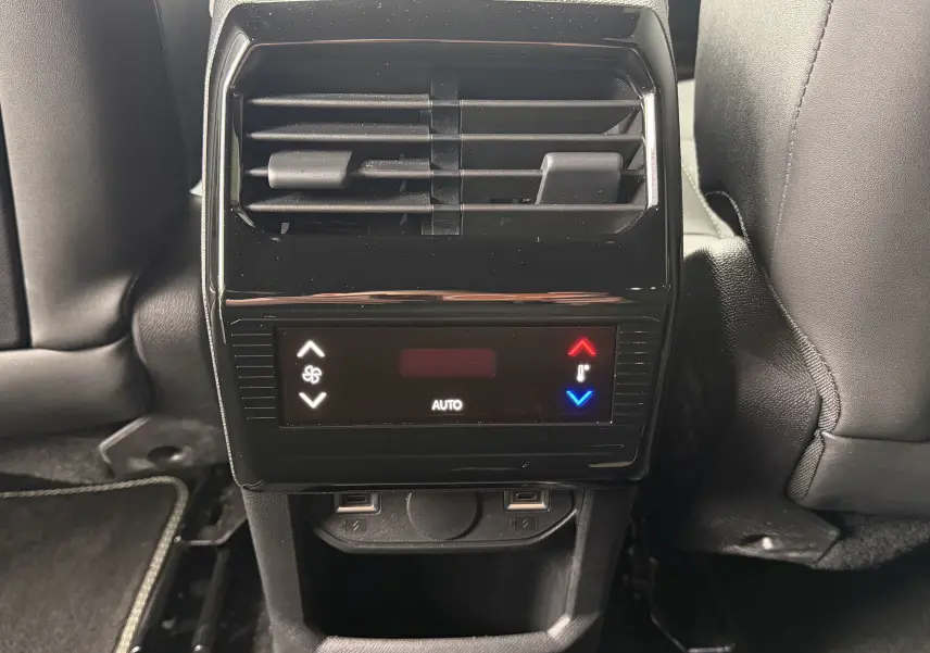 Vue rapprochée de la console arrière noire avec commandes de climatisation et prises USB du Peugeot 5008 Hybrid 145 GT blanc.