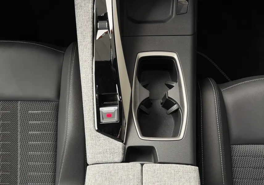 Vue plongeante sur la console centrale du Peugeot 5008 Hybrid 145 GT, avec porte-gobelets et accoudoirs tissu gris et cuir noir.
