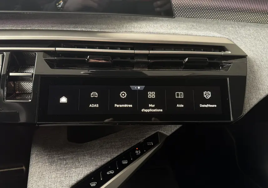 Vue rapprochée de l’écran tactile central et de la console avec commandes tactiles dans l’habitacle gris du Peugeot 5008 Hybrid 2025.