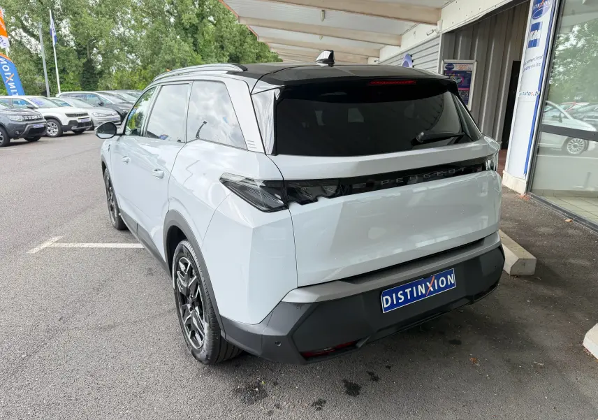 Vue 3/4 arrière d’un Peugeot 5008 HYBRID 145 e-DCS6 GT blanc Okenite avec toit noir et jantes alliage 19 pouces.