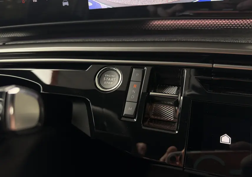 Gros plan sur la console centrale noire brillante du Peugeot 5008 Hybrid 145 e-DCS6 GT avec bouton start/stop et commandes de boîte auto.