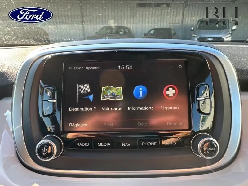 Écran tactile central de la FIAT 500X argentée, vue de face, avec interface de navigation et commandes audio visibles.