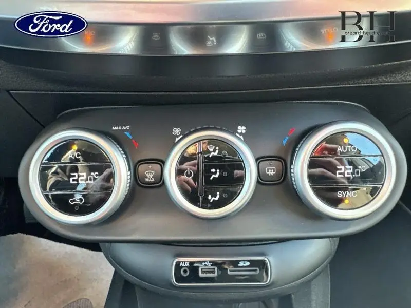 Panneau de commande de climatisation avec réglages digitaux et connectiques USB, AUX, SD, intérieur d'une Fiat 500X argentée.